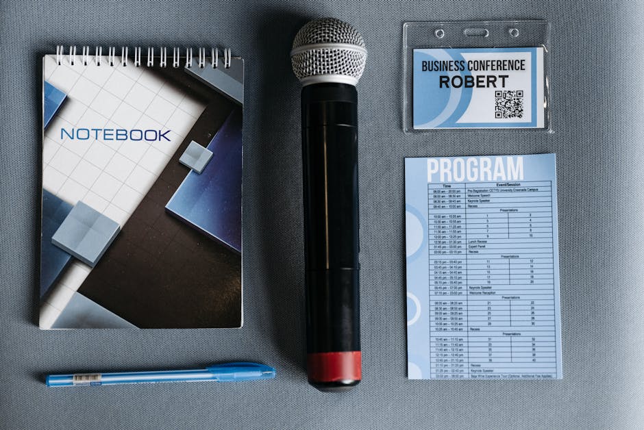Flat lay of conference essentials including microphone, notebook, and program.